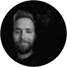 A black and white photograph of a bearded man with a black cat on his shoulder in a circular frame